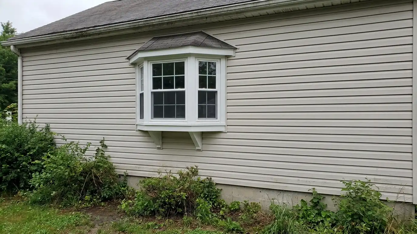 After: A small flat window replaced by a welcoming bay window | Music City Windows After: a cottage front wall with a white bay window projecting from the wall with a small seat roof and flower boxes