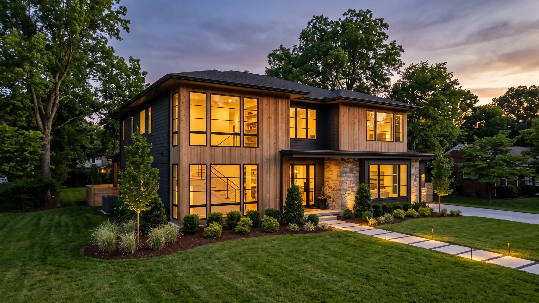 Music City Windows | Nashville, TN A beautiful modern Nashville home at dusk with large black-framed windows glowing warmly, clean landscaping and a tidy lawn